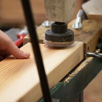 Löcher werden in die Holzbohlen gebohrt